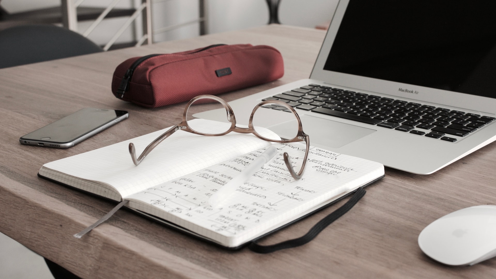 Bok, glasögon och en laptop på ett bord. Foto: Unplash.